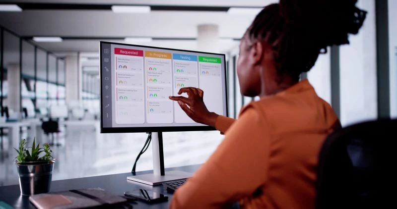 Remote team leader reviewing task board with project updates on a digital screen